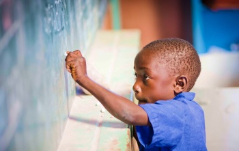 A child writes on a chalkboard