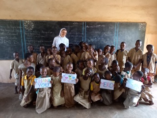 pupils and their teacher gathered in front of the chalkboard for a photo